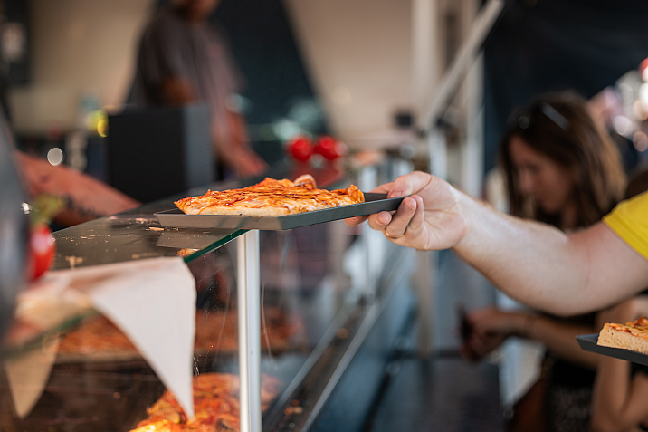 A fan getting pizza on a reusable plate.